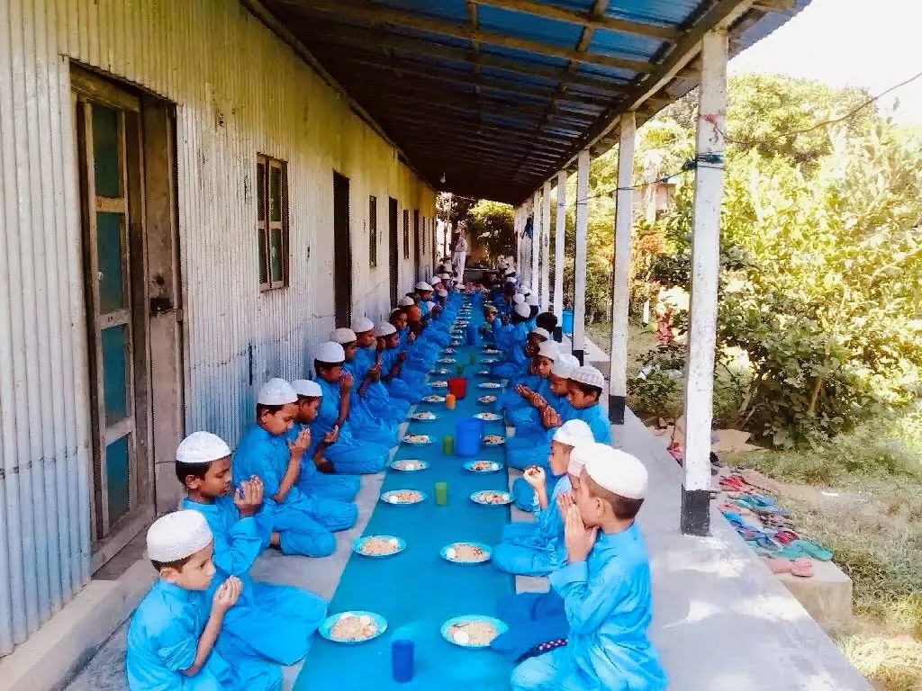 Children eating along the corridor of the original tin-shed campus